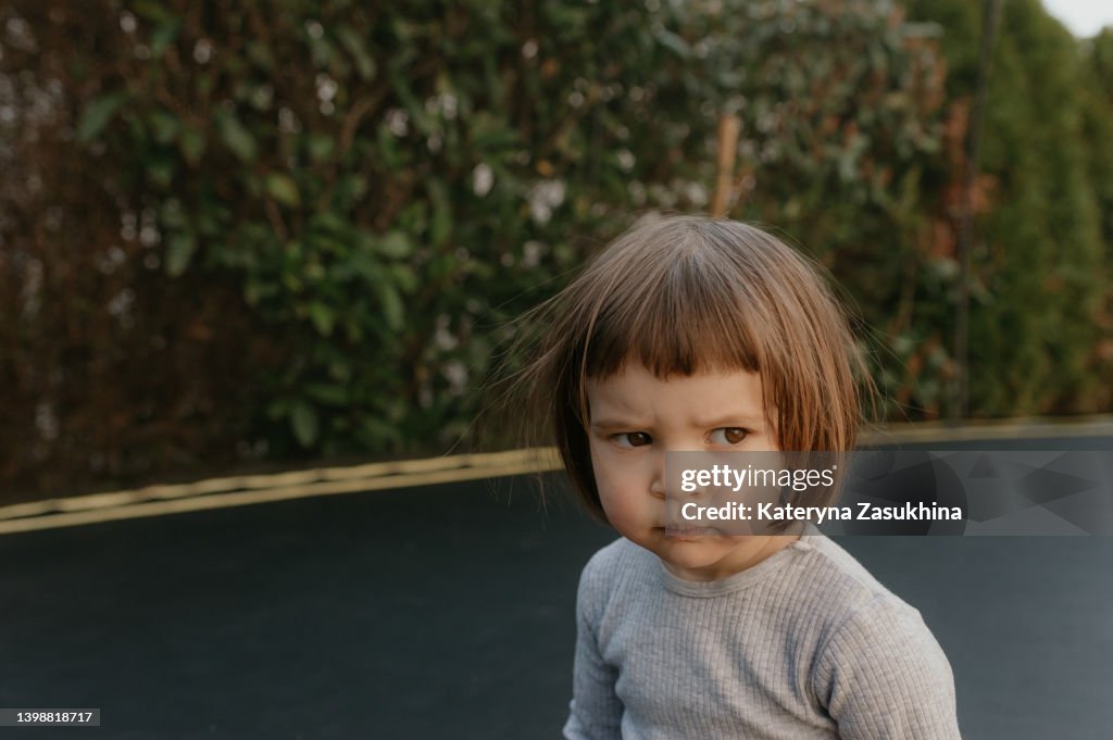 A closeup portrait of a frowned toddler girl with electrified hair