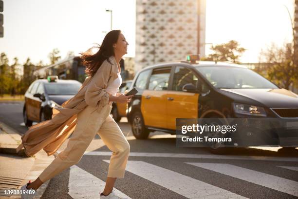 una giovane donna attraversa la strada durante l'ora di punta. - corsa contro il tempo foto e immagini stock