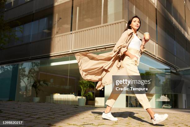 a businesswoman in a hurry during rush hour. - trench coat stock pictures, royalty-free photos & images