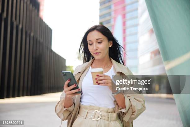 vista de cerca de una mujer de negocios con un teléfono inteligente y una taza de café. - social media fotografías e imágenes de stock