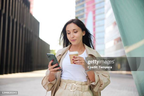 vista de cerca de una mujer de negocios con un teléfono inteligente y una taza de café. - parte de fotografías e imágenes de stock