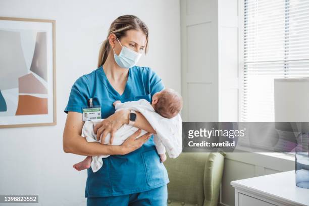 pediatrician nurse taking care of newborn baby at hospital ward. - protective face mask happy stock pictures, royalty-free photos & images