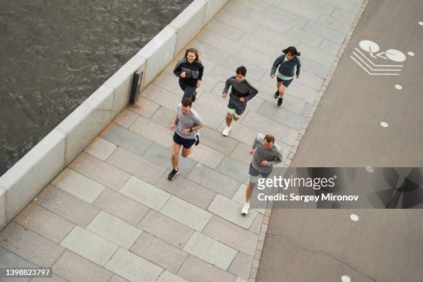 friends running at street near river - training center stock pictures, royalty-free photos & images