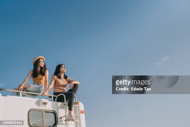 asian chinese lesbian couple enjoying scenic view on top of campervan outdoor road trip during weekend morning - asian happy adventure stock pictures, royalty-free photos & images