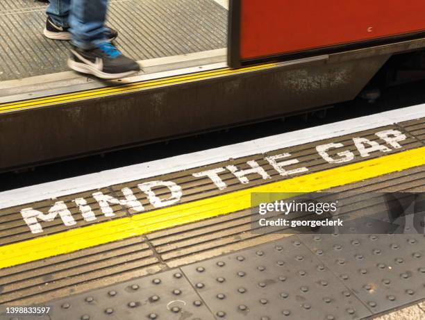 passenger stepping off london underground train - standing apart stock pictures, royalty-free photos & images