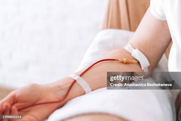 girl sitting in chair donates blood - blood donation imagens e fotografias de stock