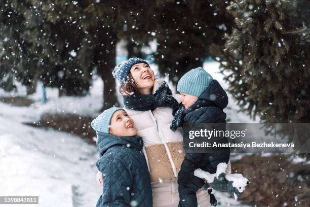 mom with son and daughter catching snow with their hands - family snow stock pictures, royalty-free photos & images