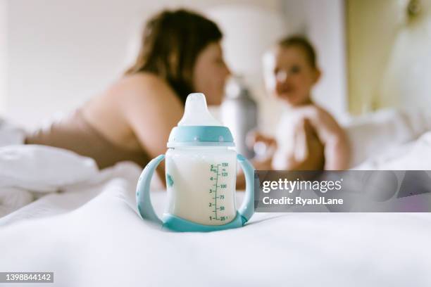 babynahrungsflasche im vordergrund von mutter und kind - milchpulver stock-fotos und bilder