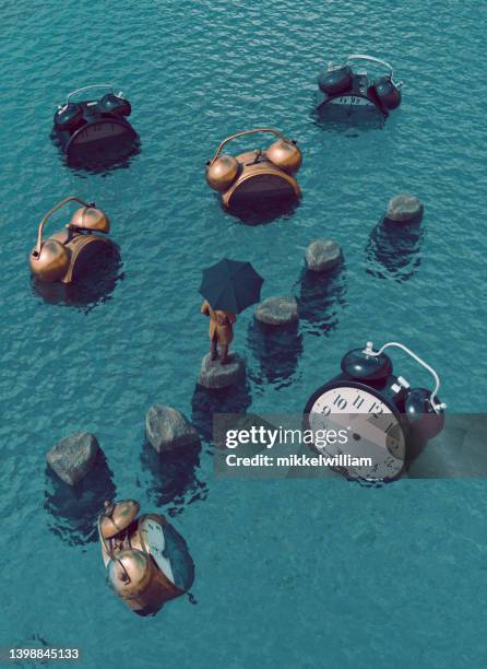 concept image of time illustrated with big alarm clocks trapped in the sea - dream big stockfoto's en -beelden