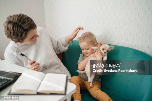 young mother with cancer remission with her family, baby son and puppy at home. cancer patients and family support concept - kids first aid kit stock-fotos und bilder