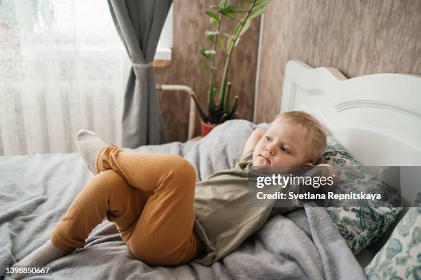 baby toddler lies on the bed. cancer patients and family support concept - kids first aid kit stock-fotos und bilder