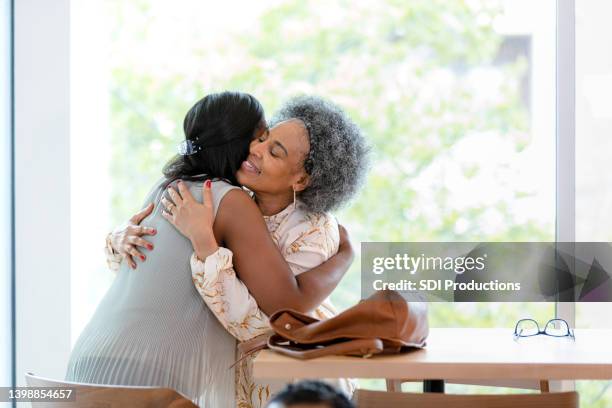 friends embrace at coffee shop as they say goodbye - granddaughter hug stock pictures, royalty-free photos & images