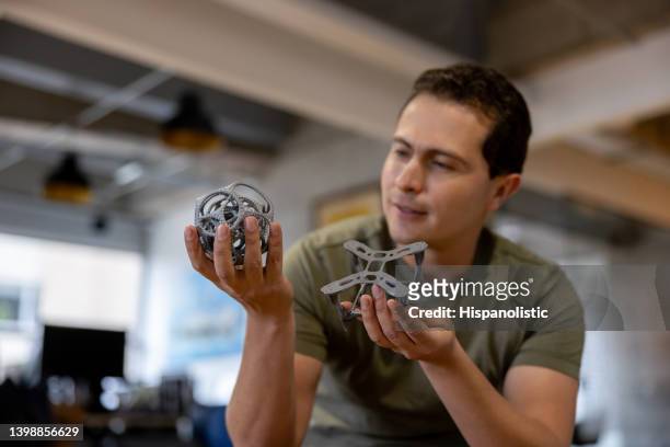 creative man holding two 3d printed objects at his office - 3 d printer stock pictures, royalty-free photos & images
