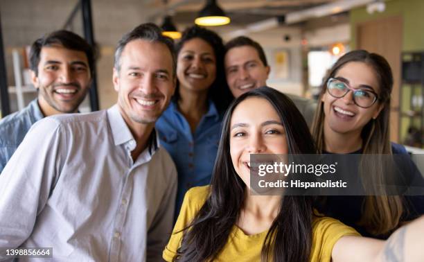 groupe heureux de collègues prenant un selfie au bureau - group photos et images de collection