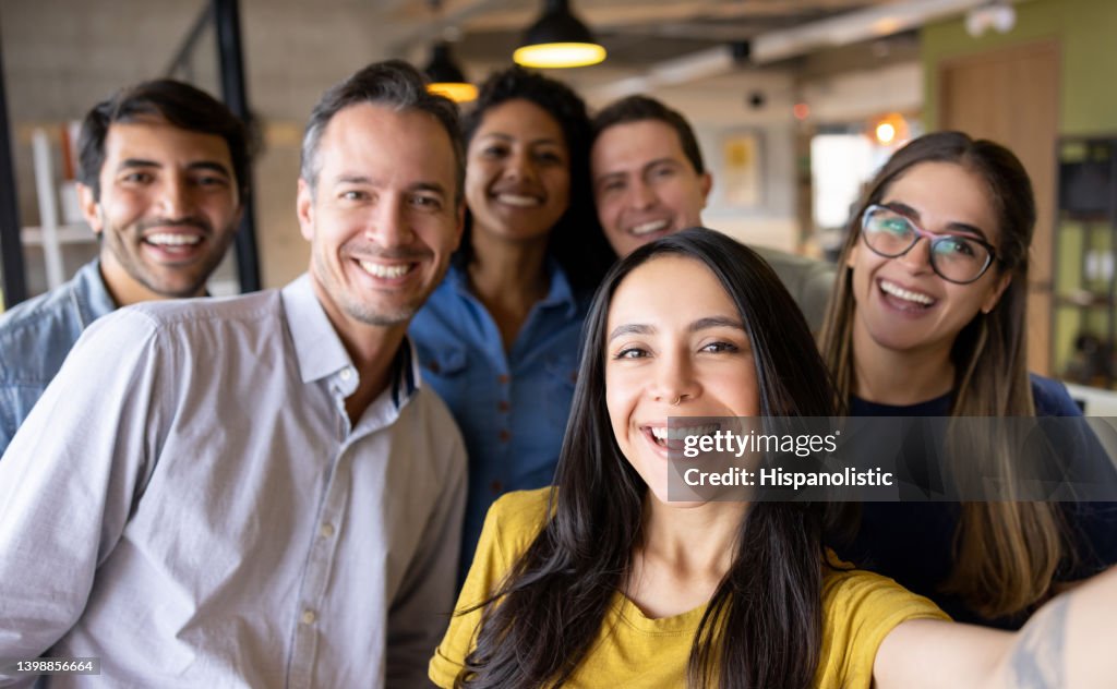 Happy group of coworkers taking a selfie at the office