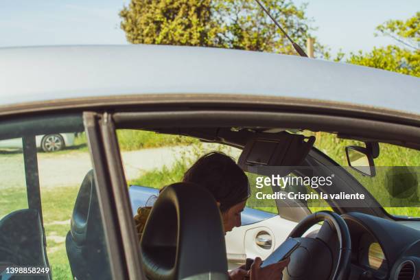 young woman looking at her smartphone inside her car, parked car - car parked stock pictures, royalty-free photos & images