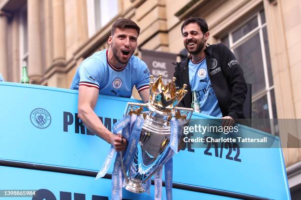 Ruben Dias lifts the Premier League trophy with Bernardo Silva of Manchester City during the Manchester City FC Victory Parade on May 23, 2022 in...