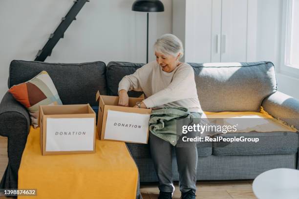 senior woman with donation box at home. - possession stock pictures, royalty-free photos & images