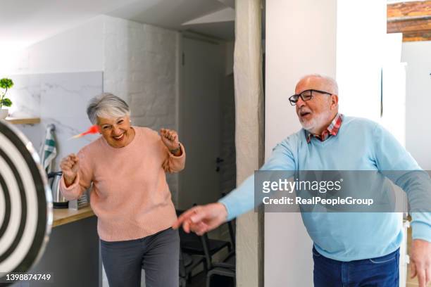 senior couple playing darts together. - throwing darts stock pictures, royalty-free photos & images