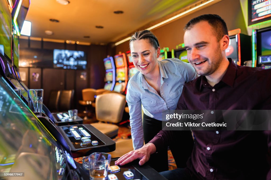 Two friends gambling on slot machine at the casino