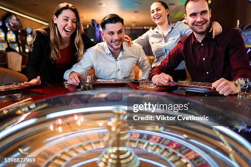 Excited group of friends playing roulette in casino Excited group of friends playing roulette in casino