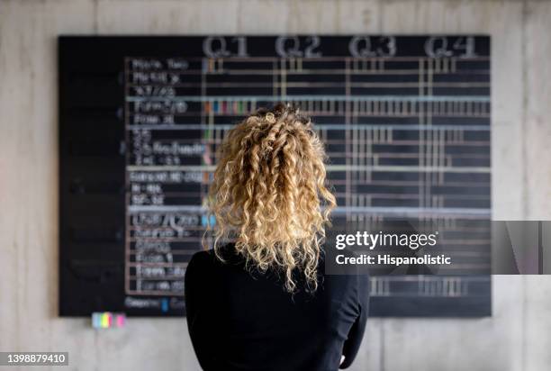 business woman looking at the project management calendar in her office - annual event stockfoto's en -beelden