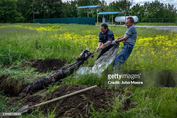 Ukrainian grave diggers, brothers who served in the Soviet military, exhume the body of a Russian soldier on May 23, 2022 on the outskirts of...