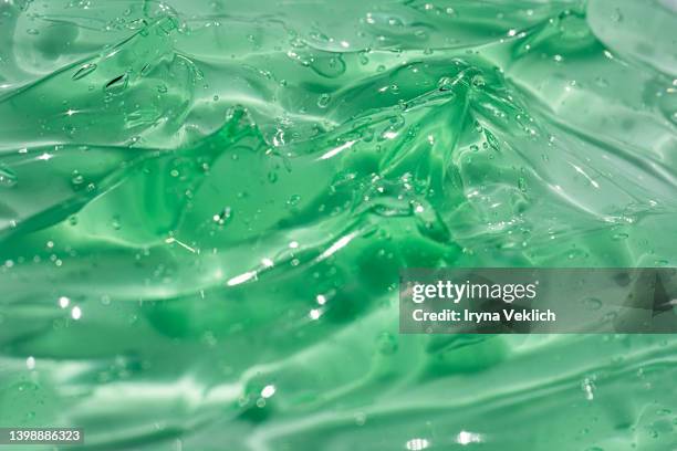 abstract background with aloe vera moisturizing cleaning cosmetic gel or face serum, essential oil with oxygen aqua bubbles on pastel green mint or basil color. - aloe vera gel stock-fotos und bilder