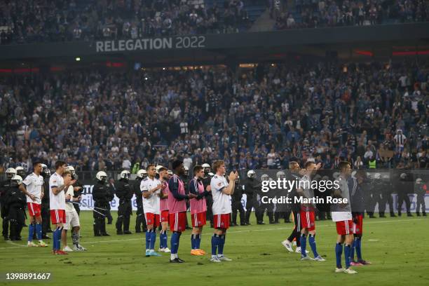 Players of Hamburg SV look dejected after their team's defeat as they stand on the pitch with police officers in the background after the Bundesliga...