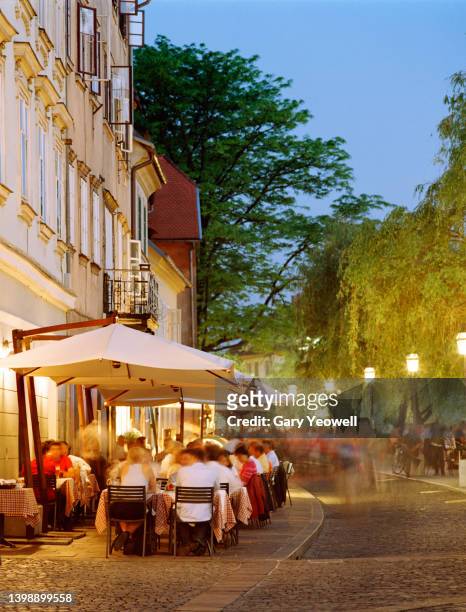 people dining along busy street in ljubljana - laibach stock-fotos und bilder