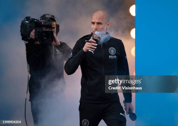 Manchester City manager Pep Guardiola is presented to the fans whilst smoking a cigar during the Manchester City FC Victory Parade on May 23, 2022 in...