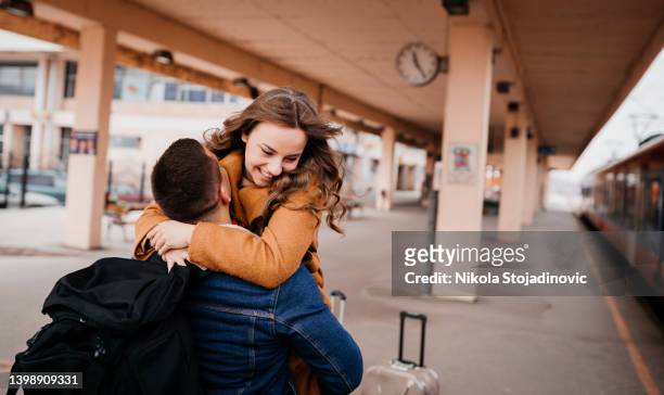 una joven pareja adolescente abrazándose en la estación de tren - reencuentro fotografías e imágenes de stock