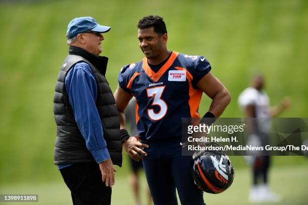 Denver Broncos quarterback Russell Wilson, right, talks with Paul Hackett, father of head coach Nathaniel Hackett, on the field during an early...