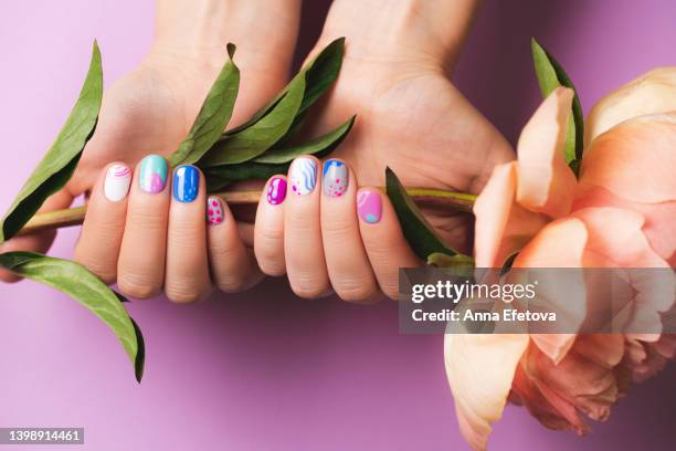 woman's hands with bright manicure holding peony flower - centro estetico foto e immagini stock
