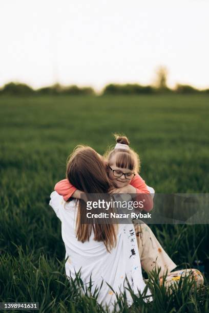 a downs syndrome girl hugs a woman - verstandelijk gehandicapt stockfoto's en -beelden