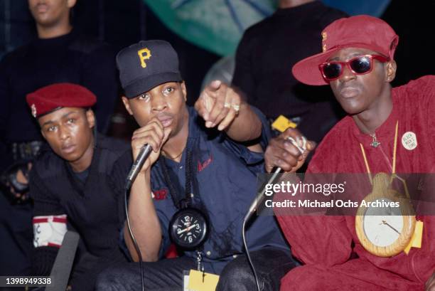 American rapper Professor Griff, wearing a red beret. American rapper Chuck D, wearing a black baseball cap, and American rapper Flavor Flav, wearing...