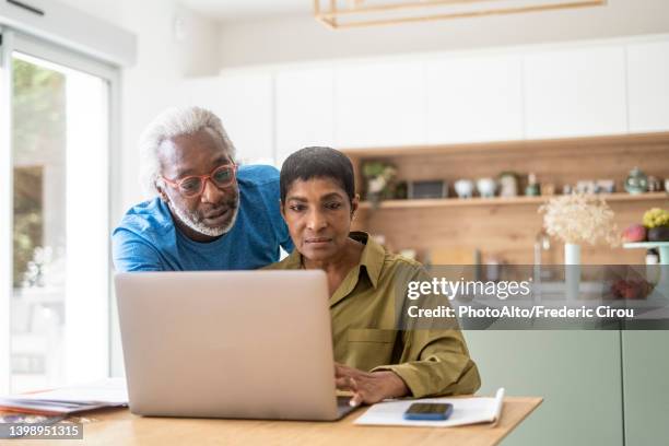 couple checking documents in kitchen - 55 60 years stock pictures, royalty-free photos & images