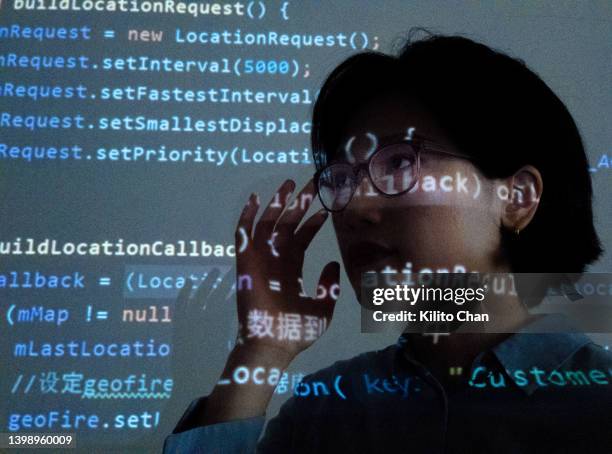asian female computer programmer looking at code on a projection screen - javascript stock-fotos und bilder