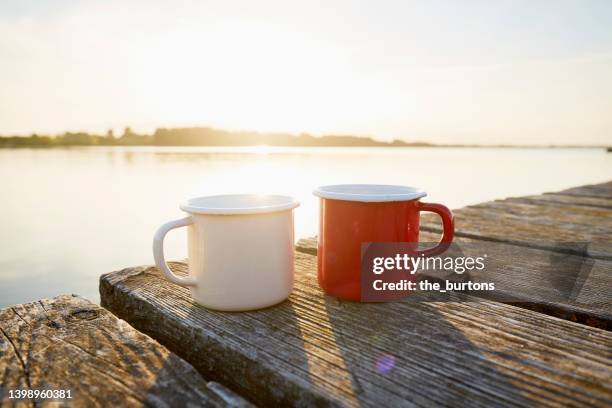 two enamel coffee cups on a jetty by the sea during sunset - ponton bois photos et images de collection