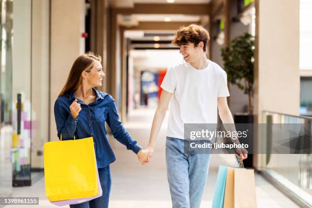 paar geht im mall center nach dem kauf von kleidung - shopping spree stock-fotos und bilder