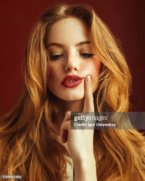 young suspicious woman with long red hair - mouth thinking stockfoto's en -beelden