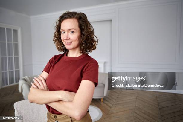 satisfied woman arms crossed in white room - tenant stock-fotos und bilder