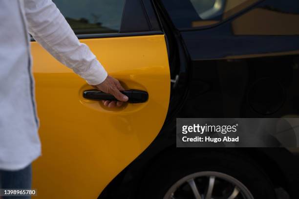 unrecognizable cab driver opening the door of his vehicle. - yellow taxi ストックフォトと画像