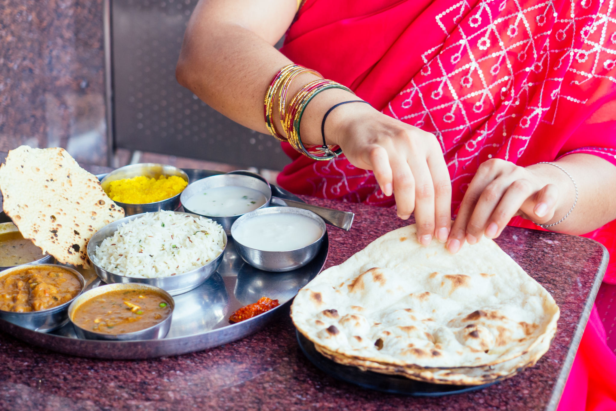 close up photo of Indian traditional vegetarian thali from rice, dal, potatoes, tomato salad on metal plate ,female hands roti india tortilla Chapati close up photo of Indian traditional vegetarian thali from rice, dal, potatoes, tomato salad on metal plate ,female hands roti india tortilla Chapati