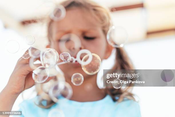 preschool girl blows soap bubbles. - seifenblasen stock-fotos und bilder