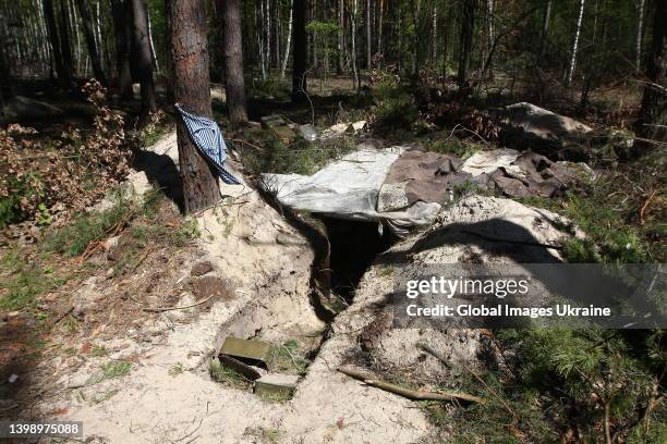 Discarded Russian military items scattered around the entrance to the dugout of Russian soldiers in a forest on May 5, 2022 in Mykulychi, Ukraine....