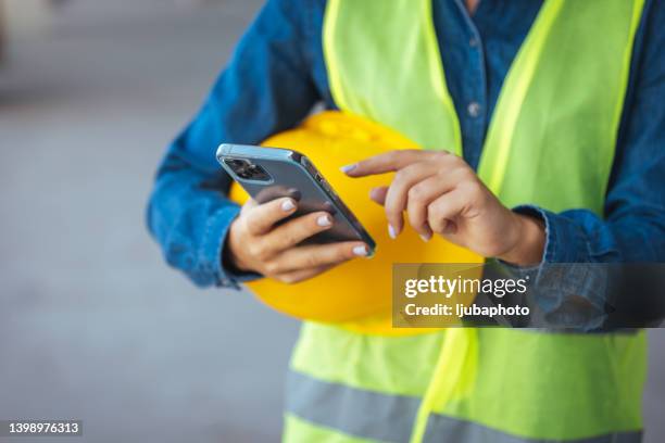 young construction worker is using mobile phone on site - builder phone stock pictures, royalty-free photos & images