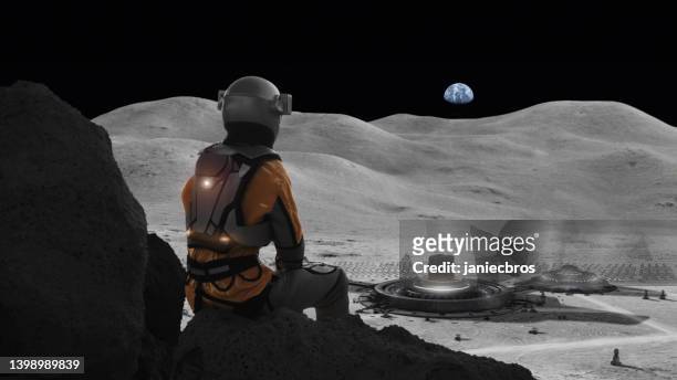 astronaut stranded on the moon missing home. distant planet earth in the sky - cosmonaut stockfoto's en -beelden