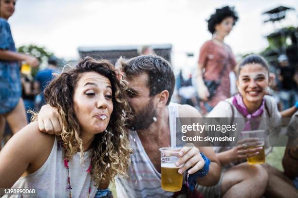 joven divirtiéndose mientras escupe cerveza en un concierto de música. - spit fotografías e imágenes de stock