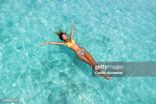 vista superior de la mujer relajada flotando en el agua en el día de verano. - floating on water fotografías e imágenes de stock